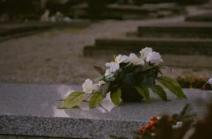 Composition de fleurs blanches déposée sur une stèle en marbre dans un cimetière.
